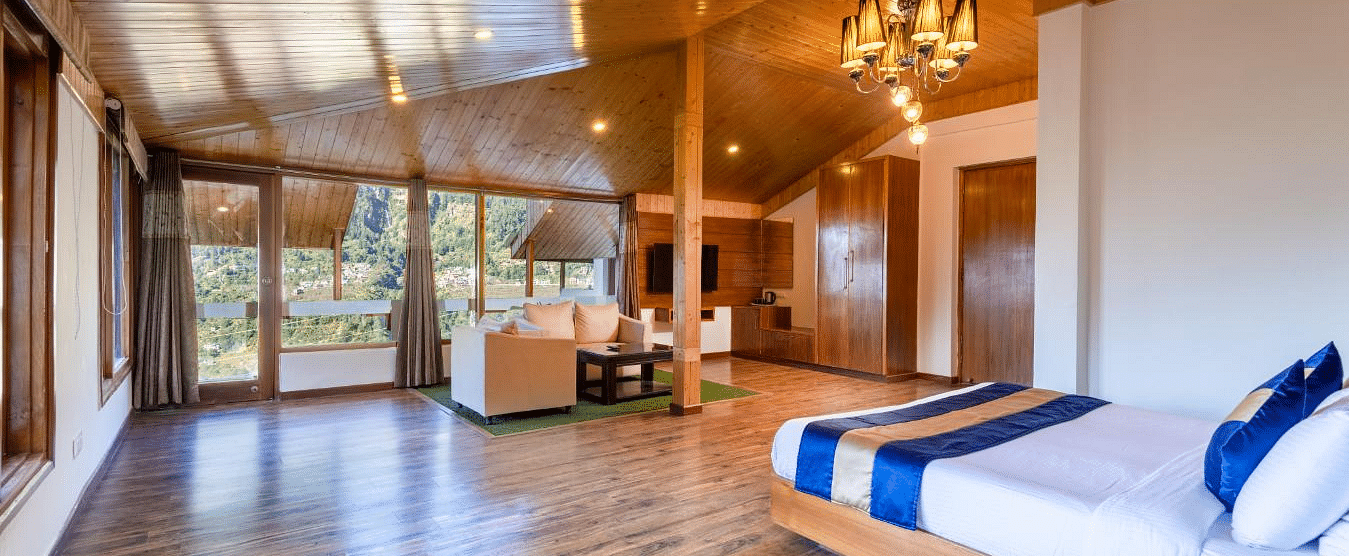 Image of a  suite with a wooden ceiling, walls, and floors, featuring a king size bed and a sitting area  | DLS Serenity Resort and Spa